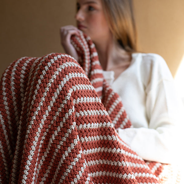 Rust and white striped knit throw blanket with thick crochet texture