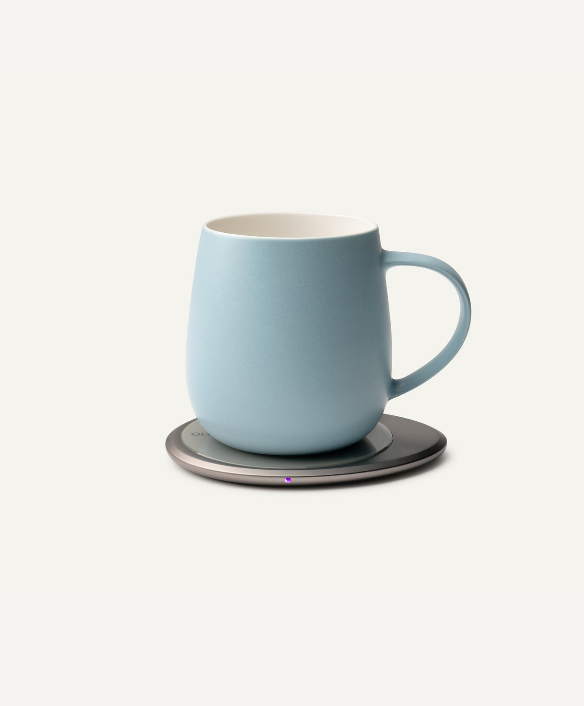 Moonmist blue self-heating mug with handle, on round dark warming base