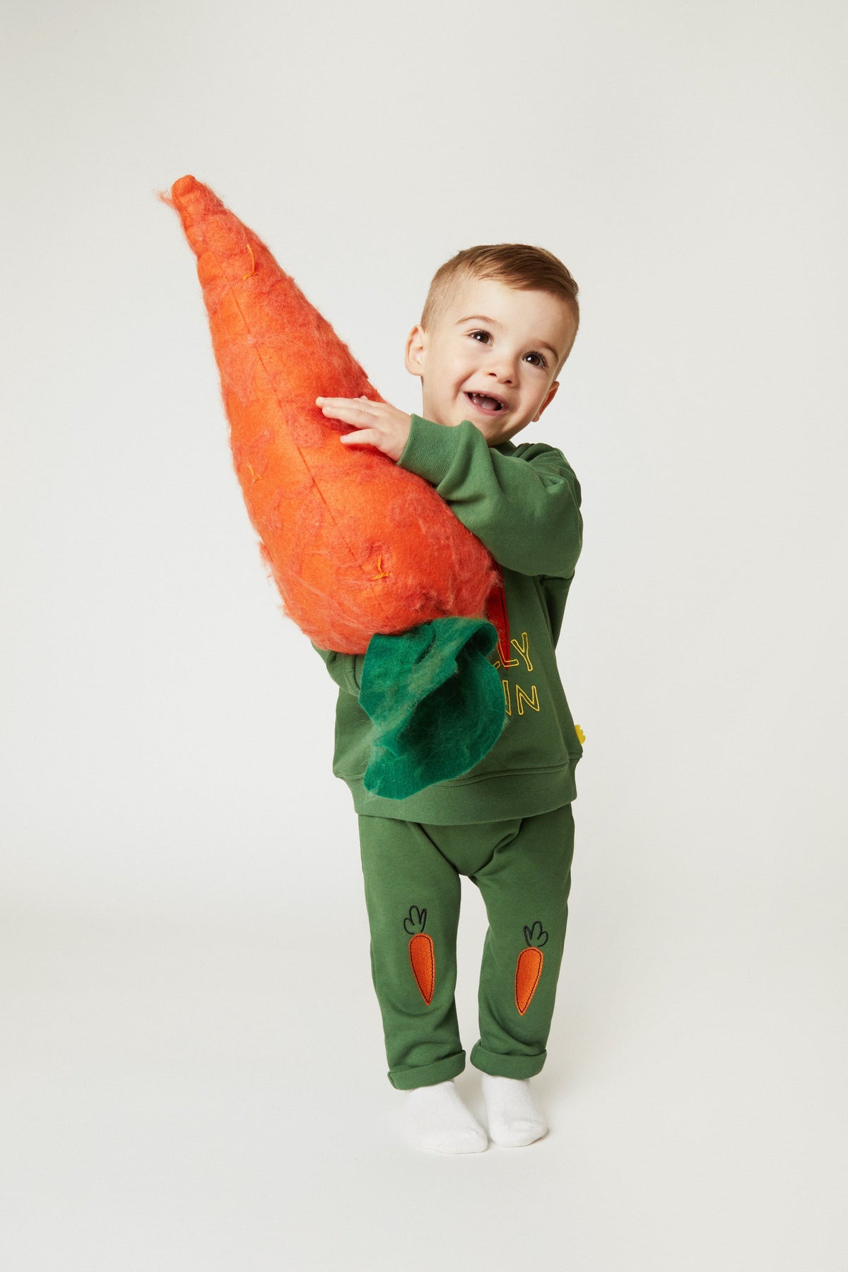 Green baby jogger pants with embroidered orange carrot designs on the legs
