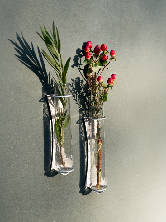 Set of 2 clear glass wall vases with metal mounts, holding red berries and greens