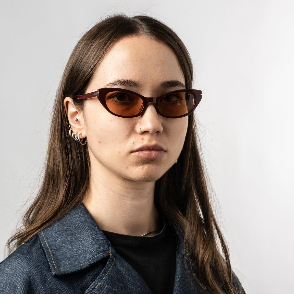 Model wearing burgundy cat-eye sunglasses with amber tinted lenses, angled front view