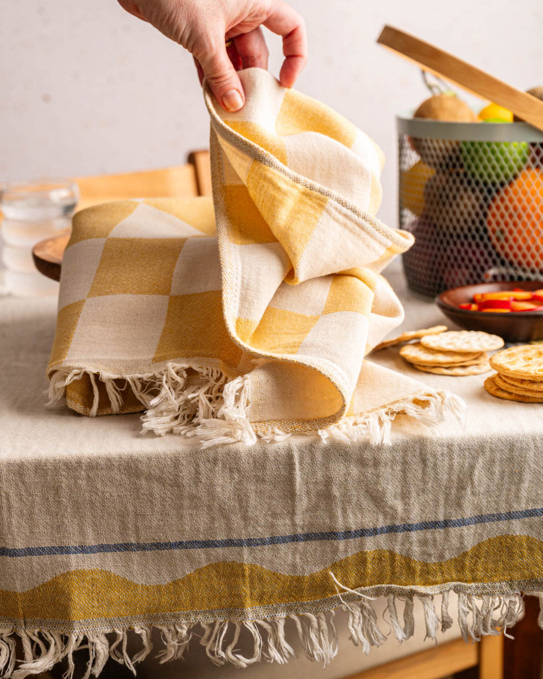 Checked kitchen towel with lemon embroidery, fringed hem, folded on a table