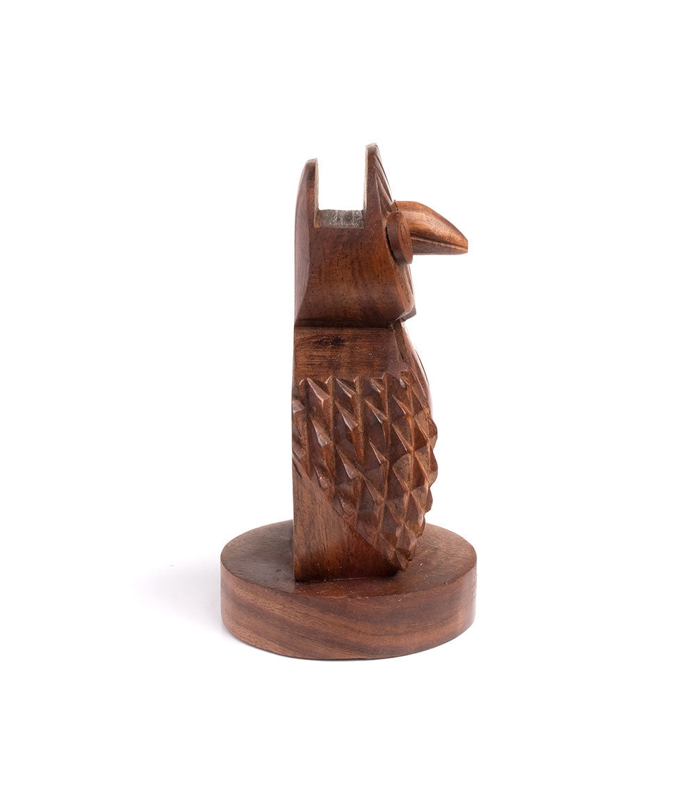 Hand-carved wooden owl eyeglass holder stand viewed from the side on a round base.