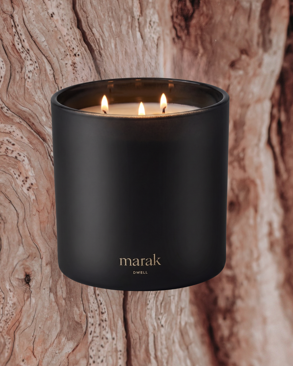 Lit marak candle in matte dark container, on wood-textured surface