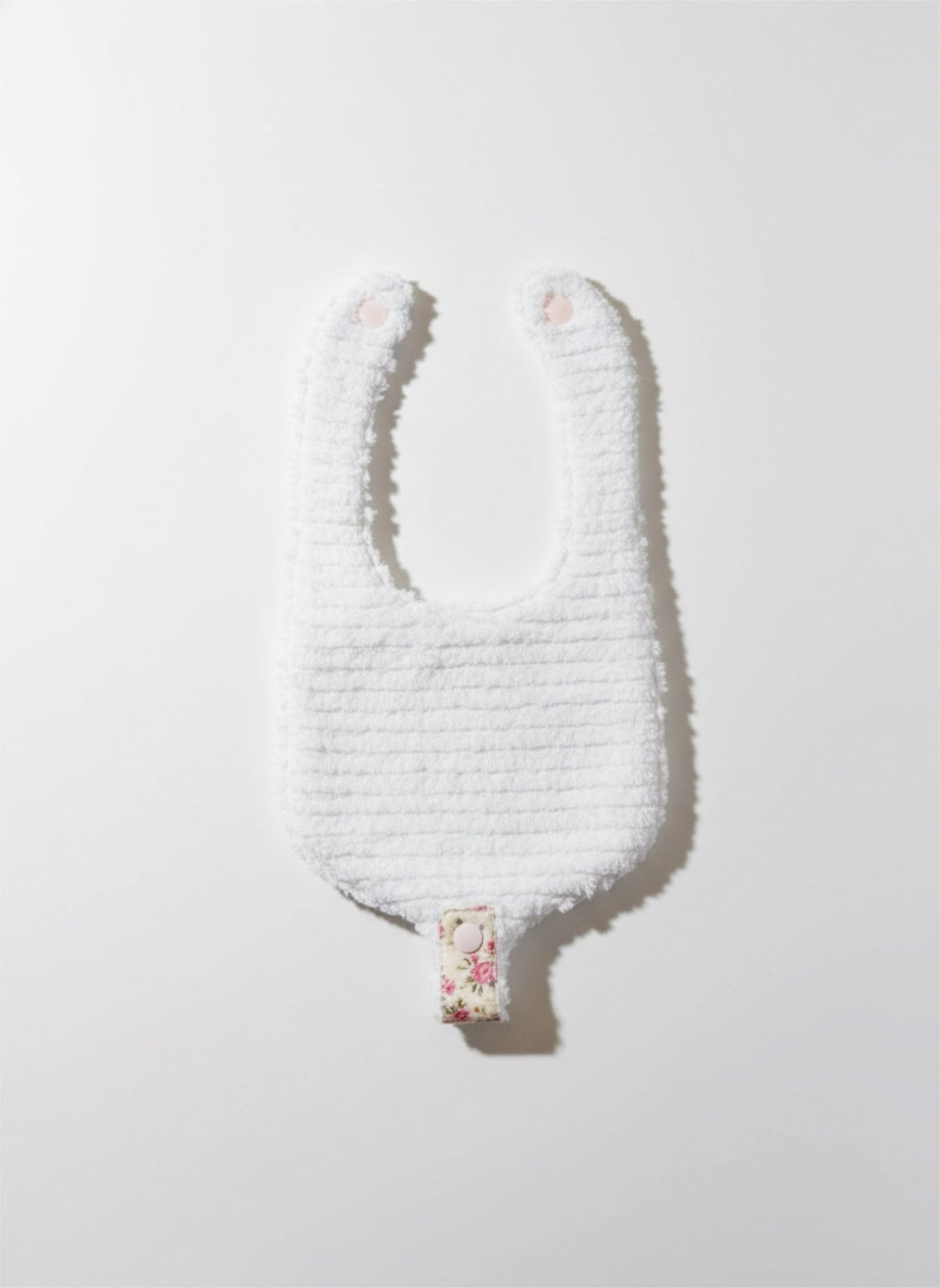 Pacifier bib with soft white textured front and small floral snap-tab detail