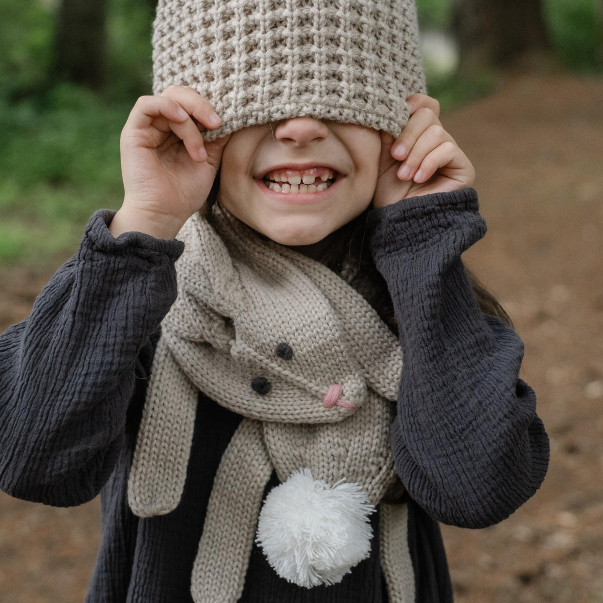 Oat beige rabbit scarf worn with its white pom-pom tail at the front