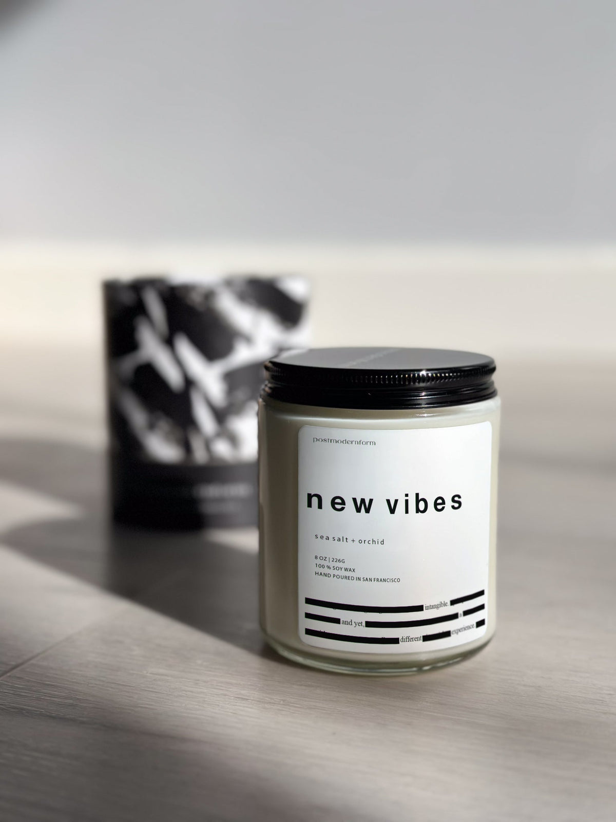 Candle in frosted glass jar with black lid and white label with simple graphics
