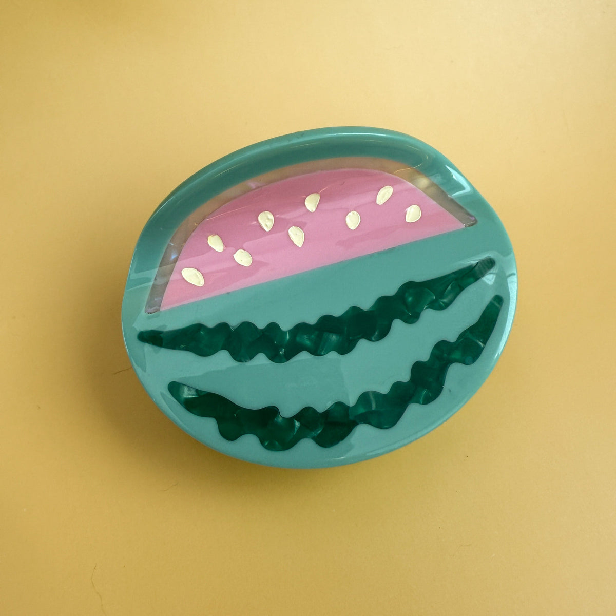 Round watermelon hair claw with teal shell and pink watermelon slice pattern