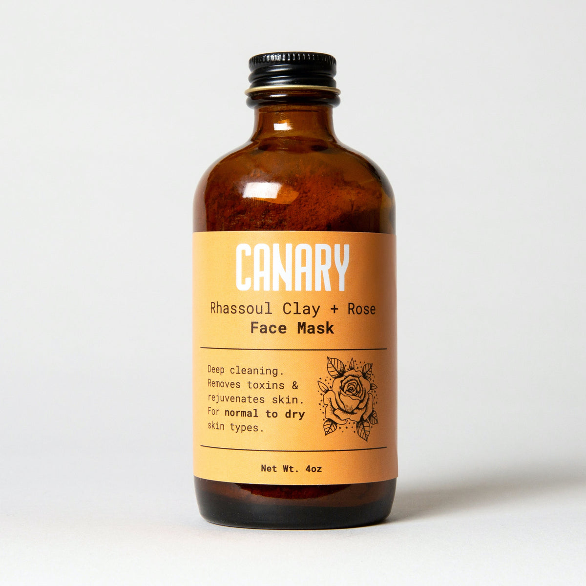 Canary Rhassoul clay and rose face mask in an amber bottle with an orange label