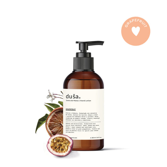 Amber hand cream bottle with black pump and grapefruit fruit beside it