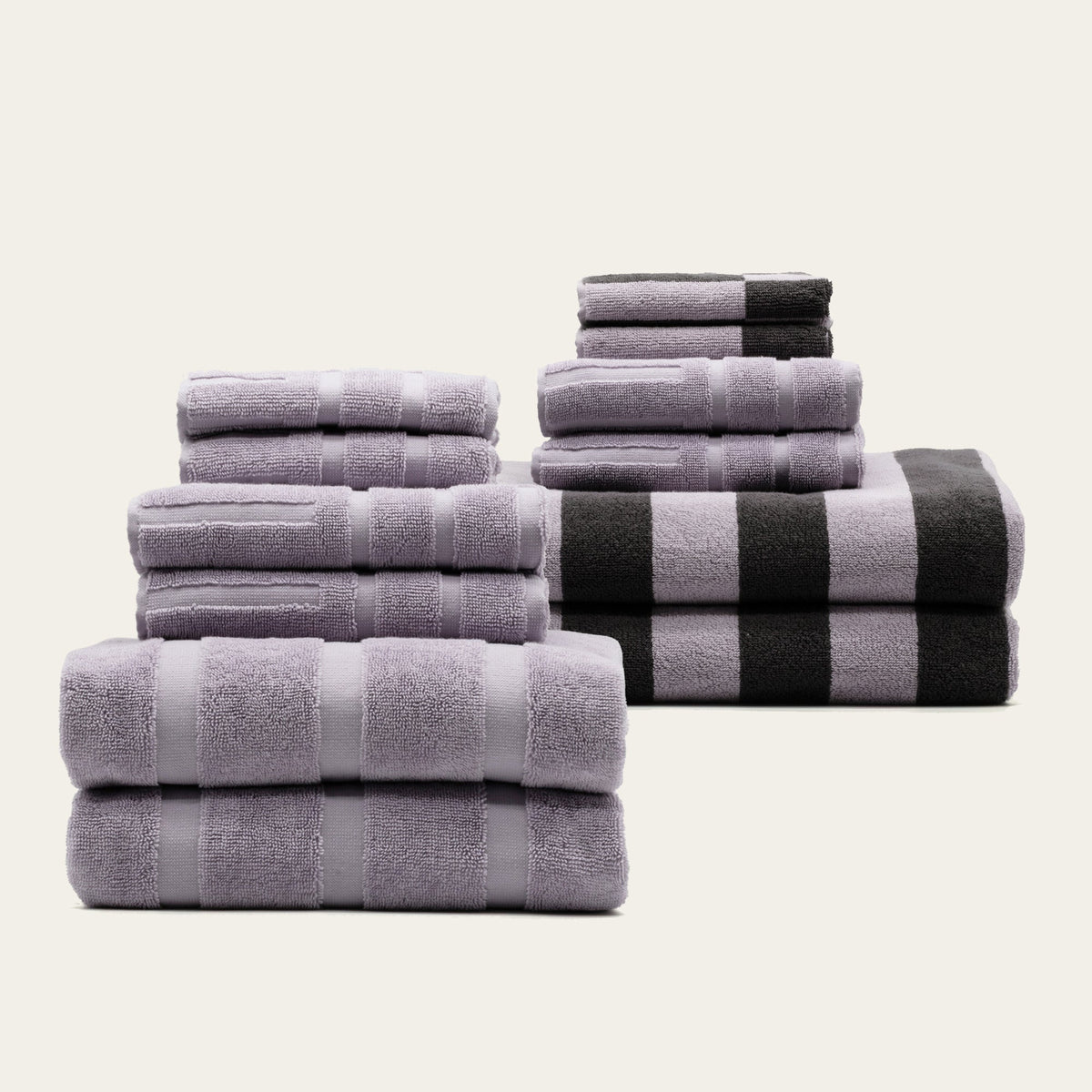 Stacked lilac and gray cotton towels, with a black-and-white stripe towel