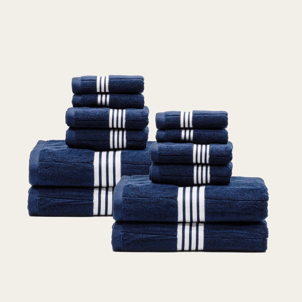 Navy cotton towels with white striped bands, mixed stack of folded towels in pairs.