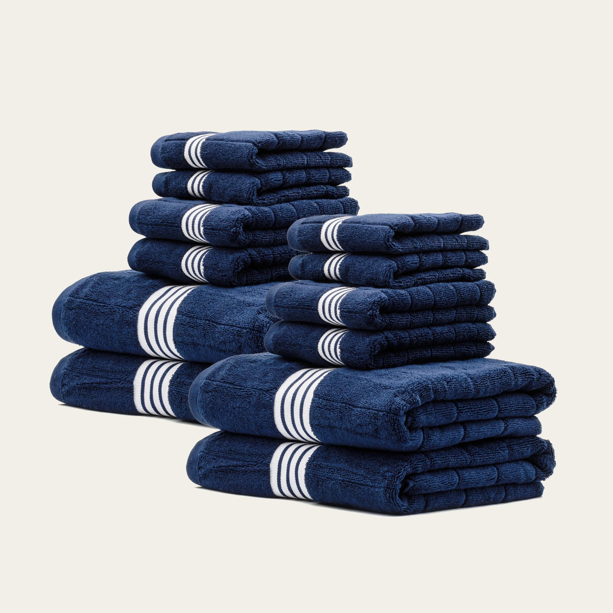Multiple navy towels stacked with white triple-stripe bands