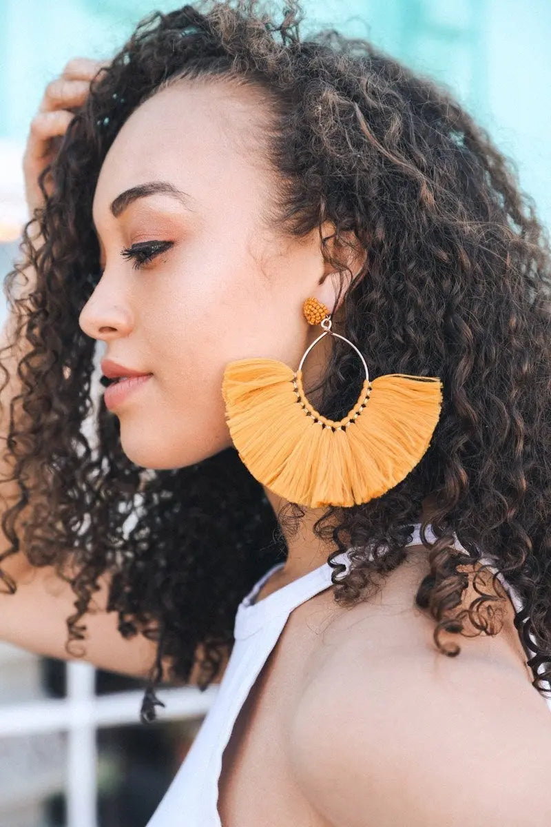 Mustard fan tassel earrings featuring rounded fringe layers and gold-tone hardware