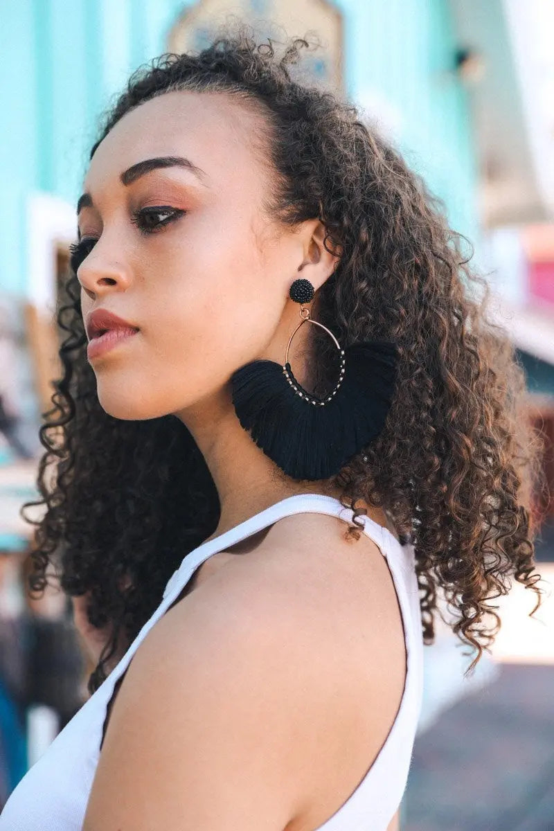 Black fan tassel earrings viewed from the side, with fringe fan and hoop base