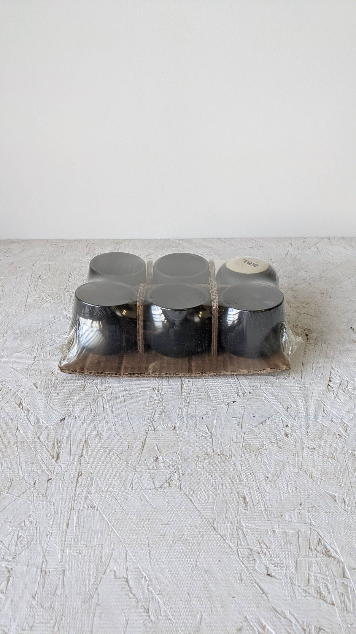 Stoneware coffee cup set in clear wrap, three dark cups in tray