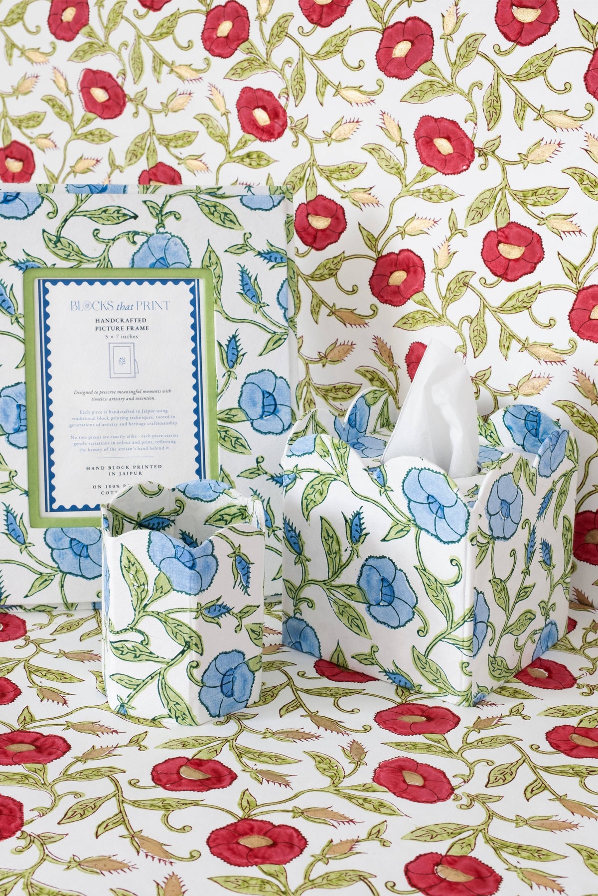 Collapsible fabric waste basket with blue flowers and red accents, holding a white tissue.
