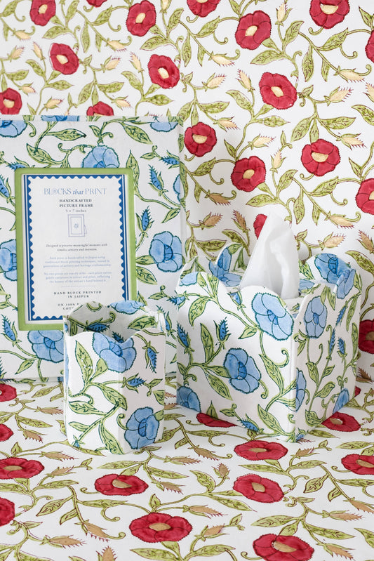 Collapsible fabric waste basket with blue flowers and red accents, holding a white tissue.