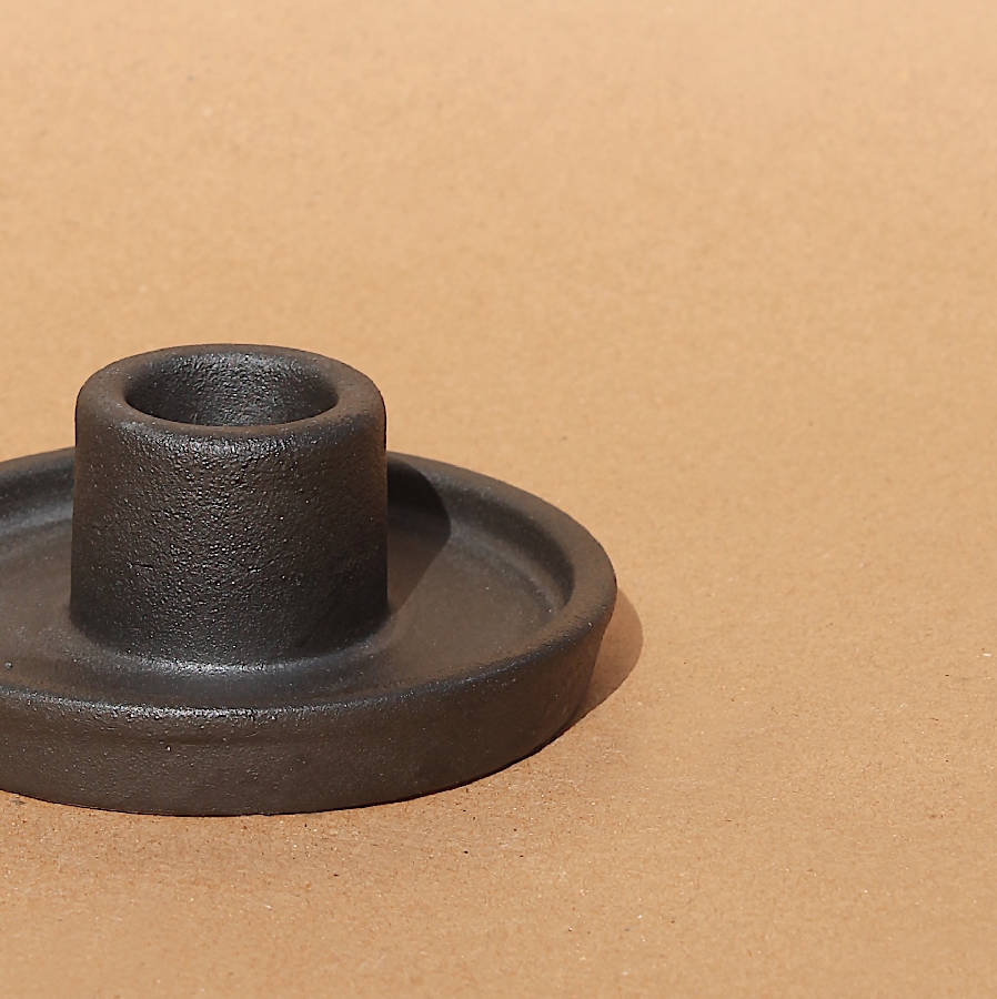 Black ceramic candle holder close-up, round base with raised center cup