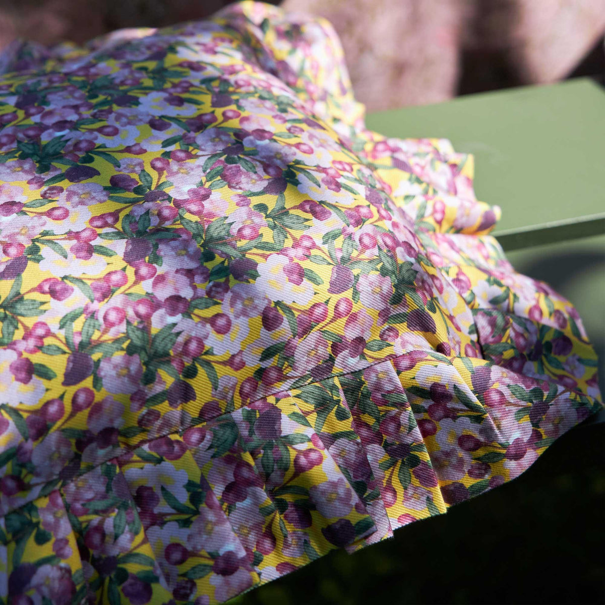 Close-up of yellow floral fabric on ruffled pillow cover with layered pleats