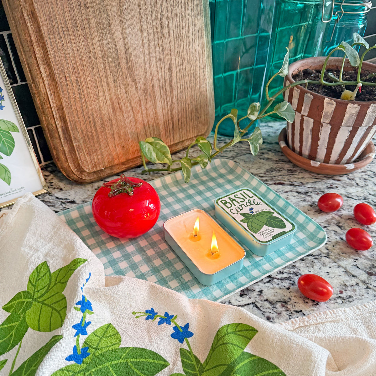 Basil and Tomato soy candle tins with lit wicks on display.