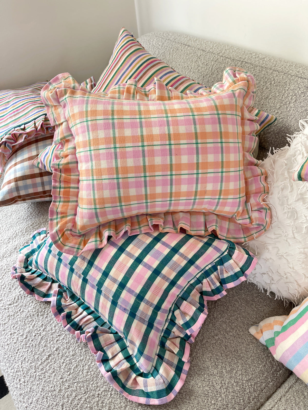 Set of plaid ruffle throw pillows layered on a sofa, colorful checked design