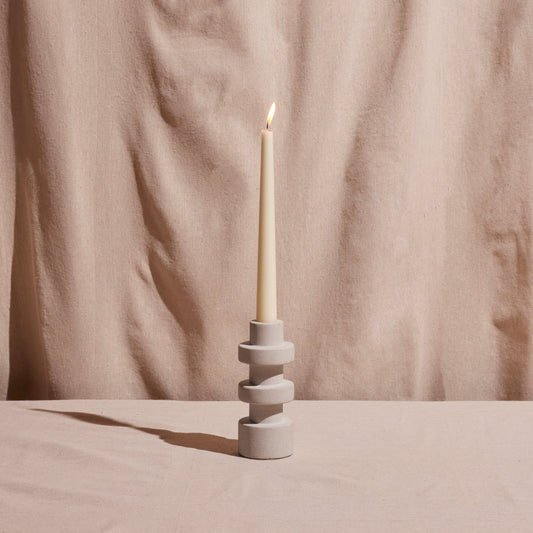 Tall candle holder with three stacked rings holding a white pillar candle.