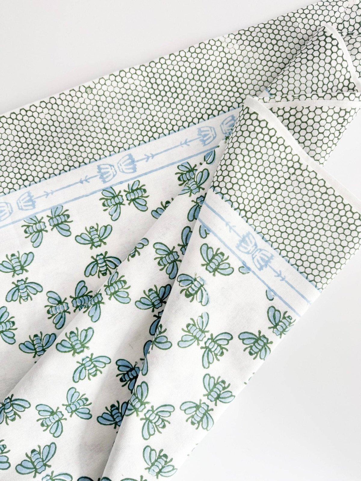 Table throw folded detail showing blue border line, floral print, and honeycomb-texture fabric.