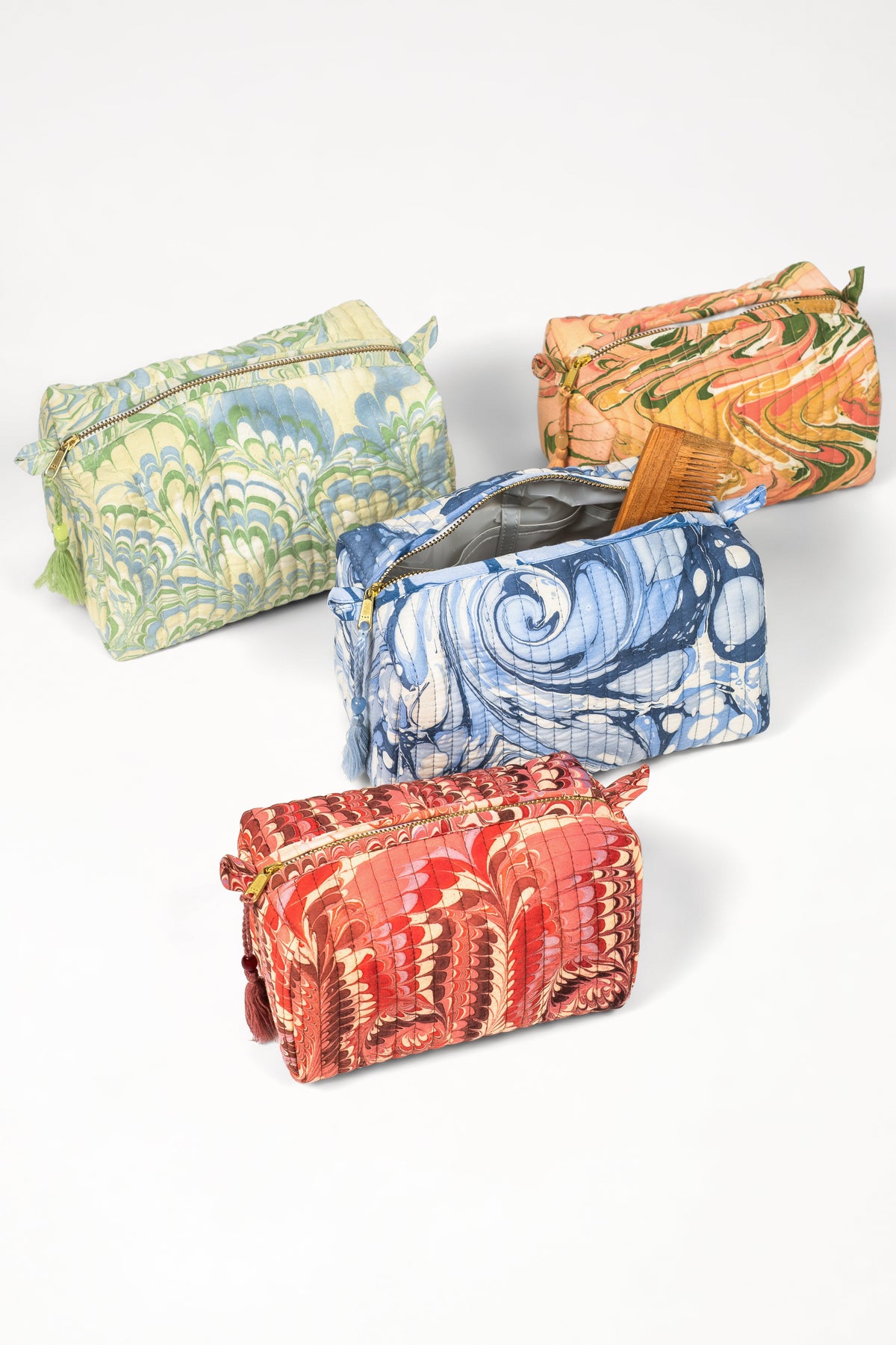 Assorted hand-marbled cosmetic bags: mint, blue, red, and orange with gold zippers