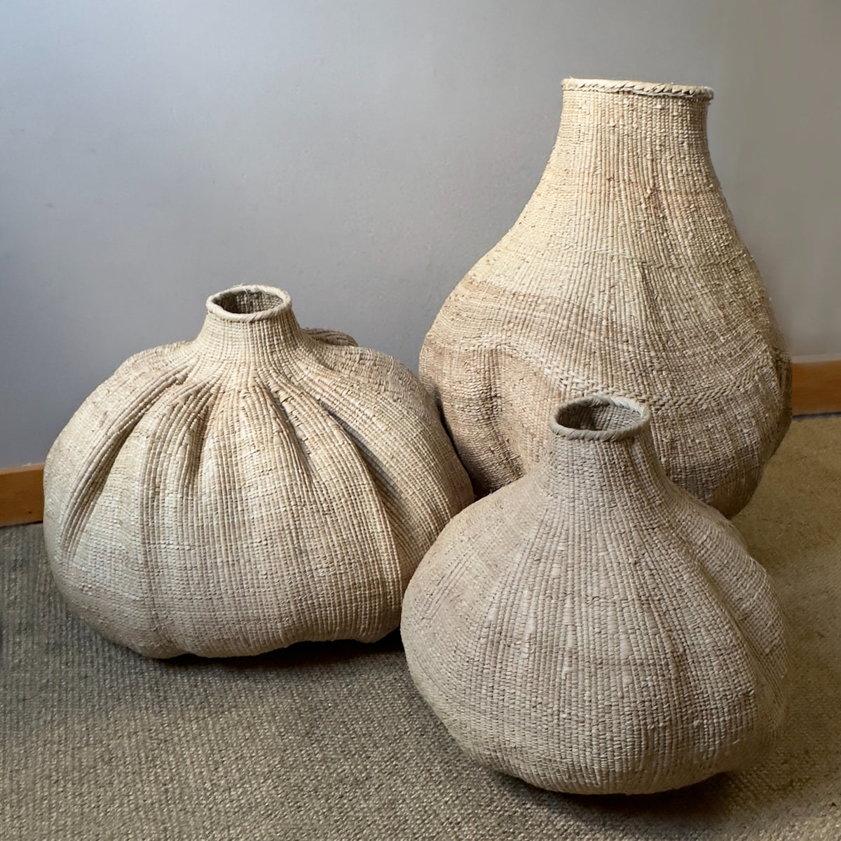 Three woven garlic baskets with bulb shapes and narrow necks, natural beige