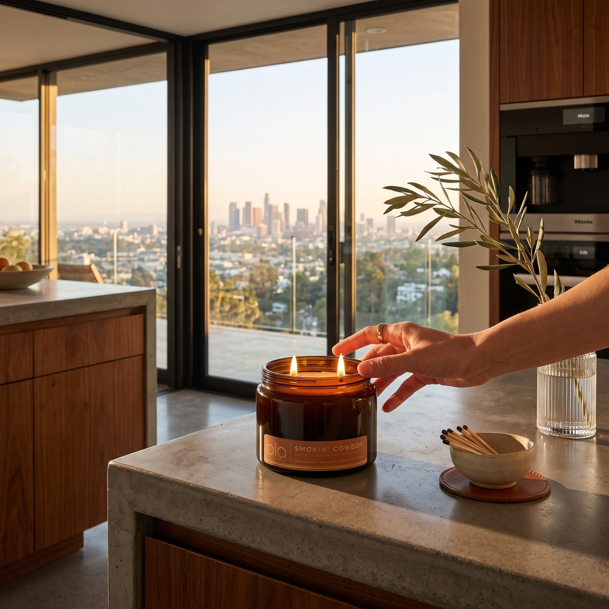 Amber glass soy candle jar with lit flame on a countertop