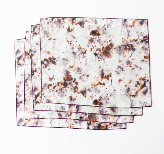 Stacked marble rose placemats with plum trim; white mottled with rose-brown speckles