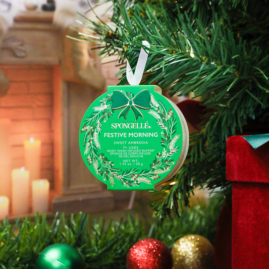 Green Festive Morning sponge wreath with bow ribbon, hanging from a branch
