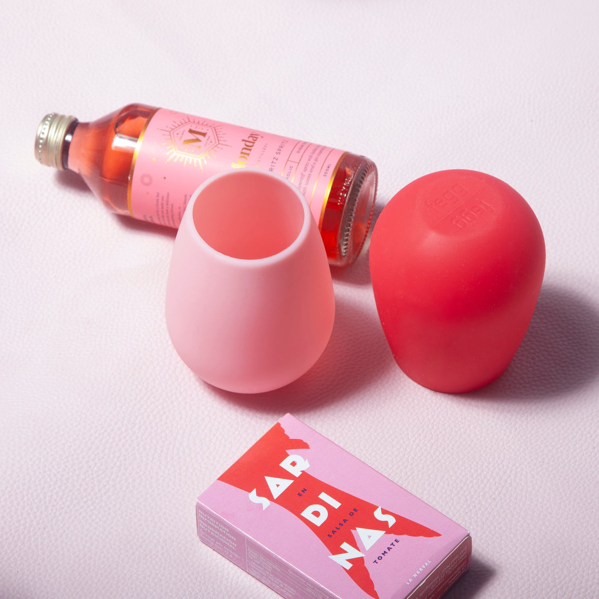 Blush pink and cherry red silicone unbreakable cups with drink bottle nearby