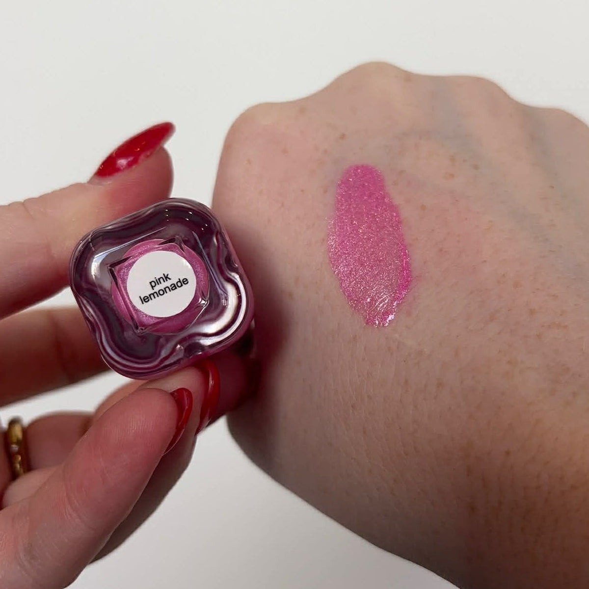 Blush Bom liquid blush swatch on arm, bottle shows Pink lemonade