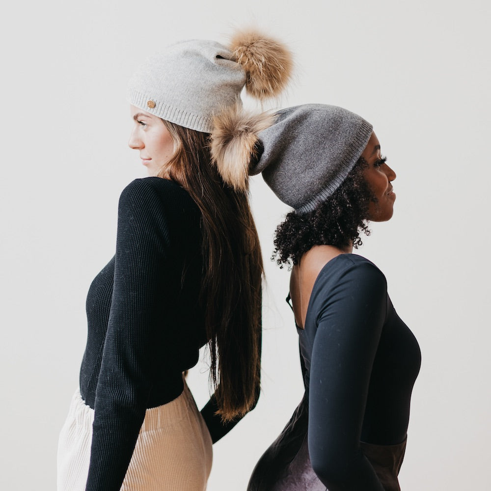Light gray and charcoal knit beanies with fur poms