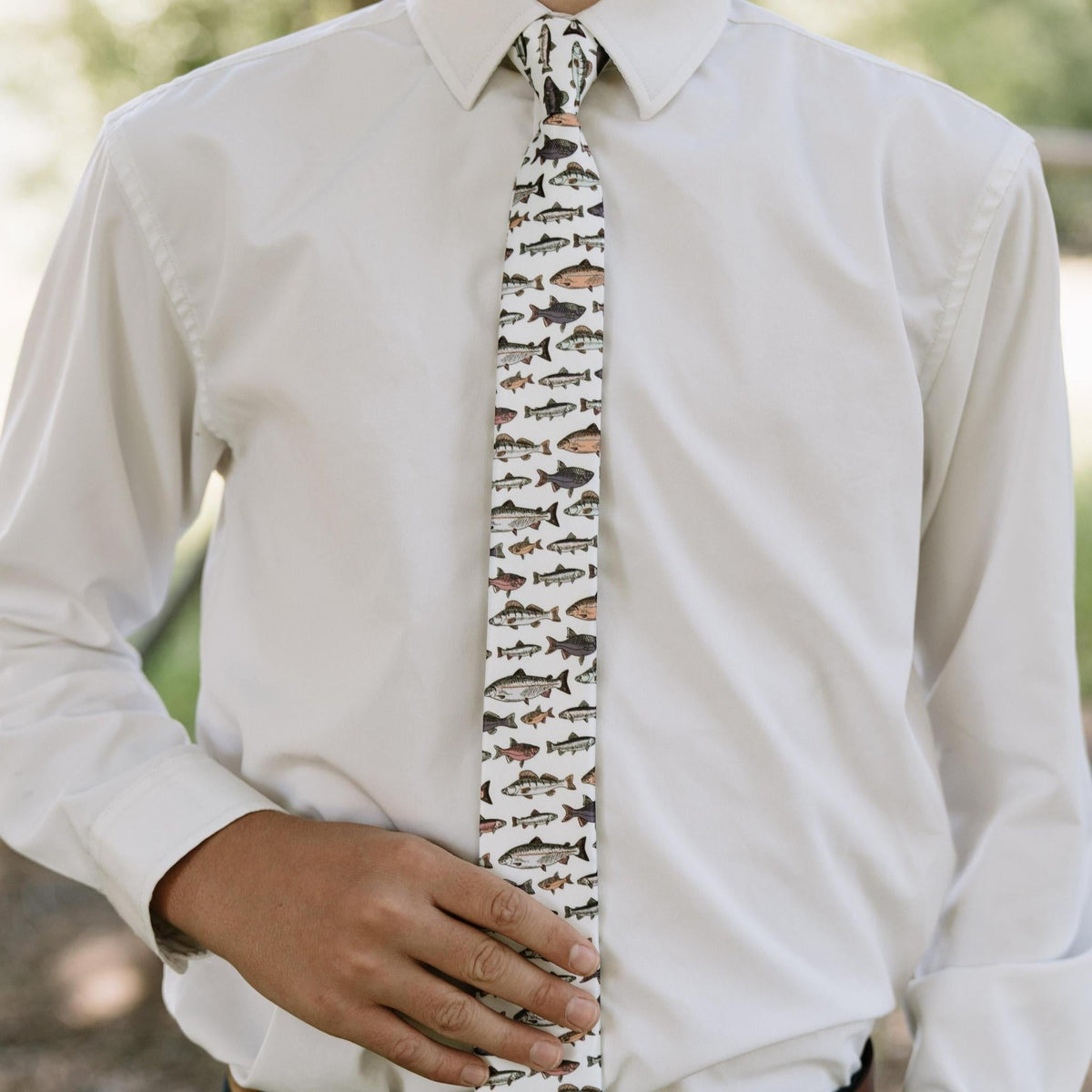Men's fish-pattern necktie centered under white shirt, white base with fish silhouettes