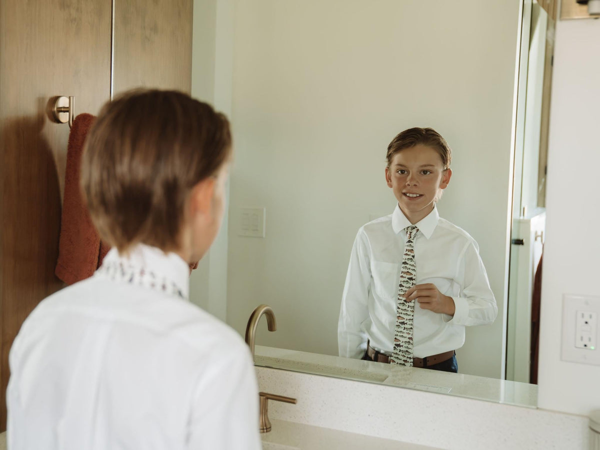 Youth necktie with fish print visible in mirror reflection on a child