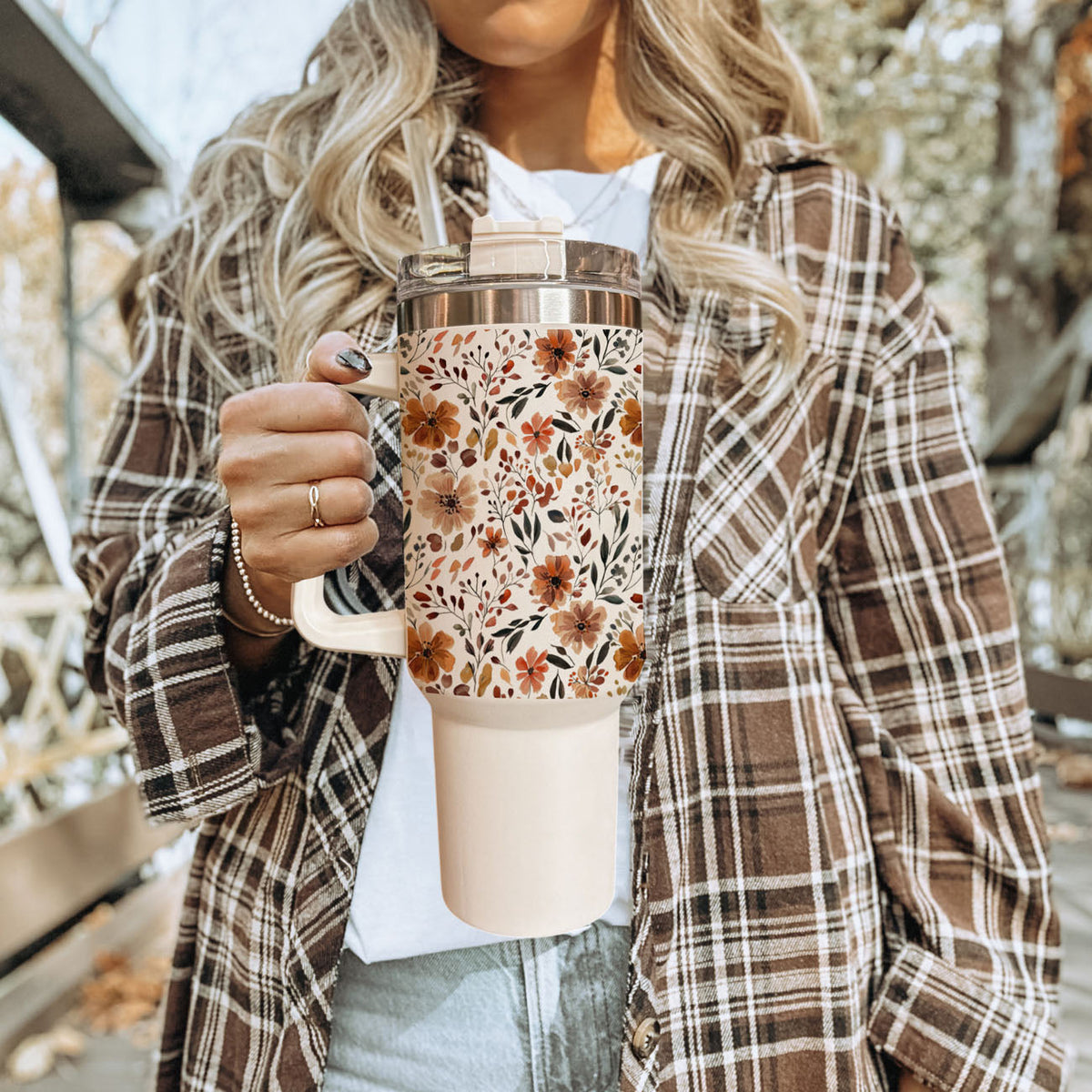 40oz floral insulated tumbler with clear lid and straw, held in front of plaid jacket