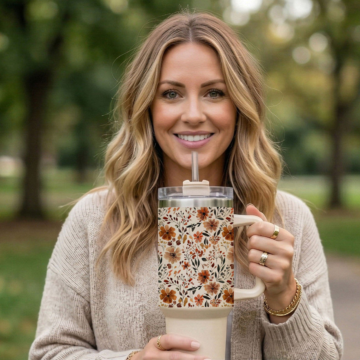 Floral tumbler with clear lid and straw, held up outdoors