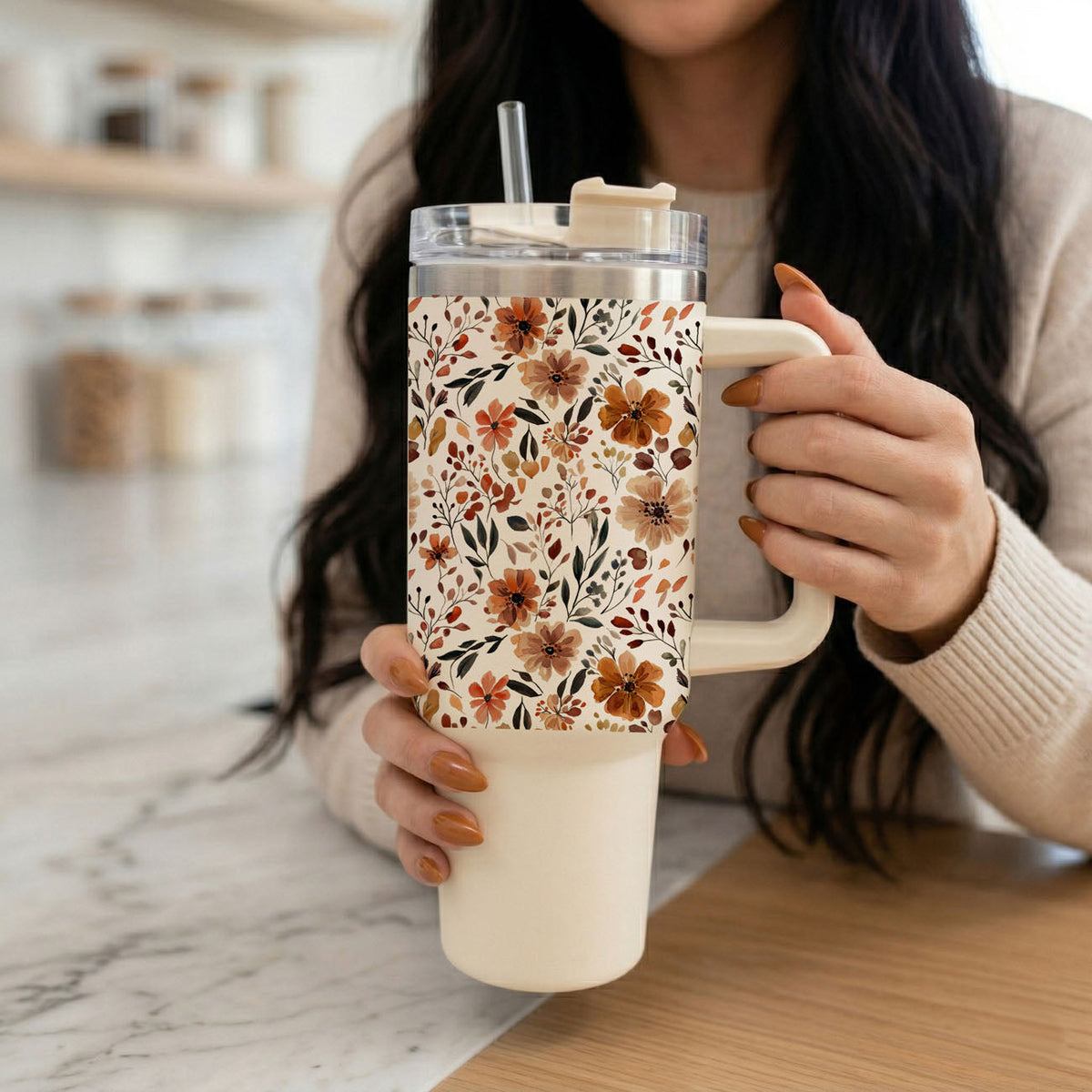 Floral tumbler with clear lid and straw, held by hands