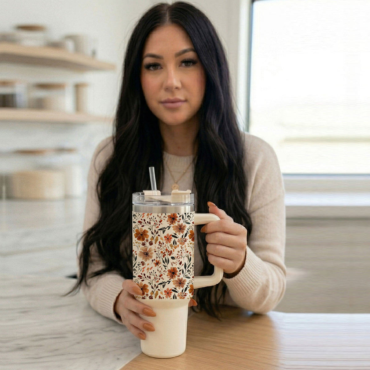 40oz floral insulated tumbler with clear lid and straw, held at kitchen table