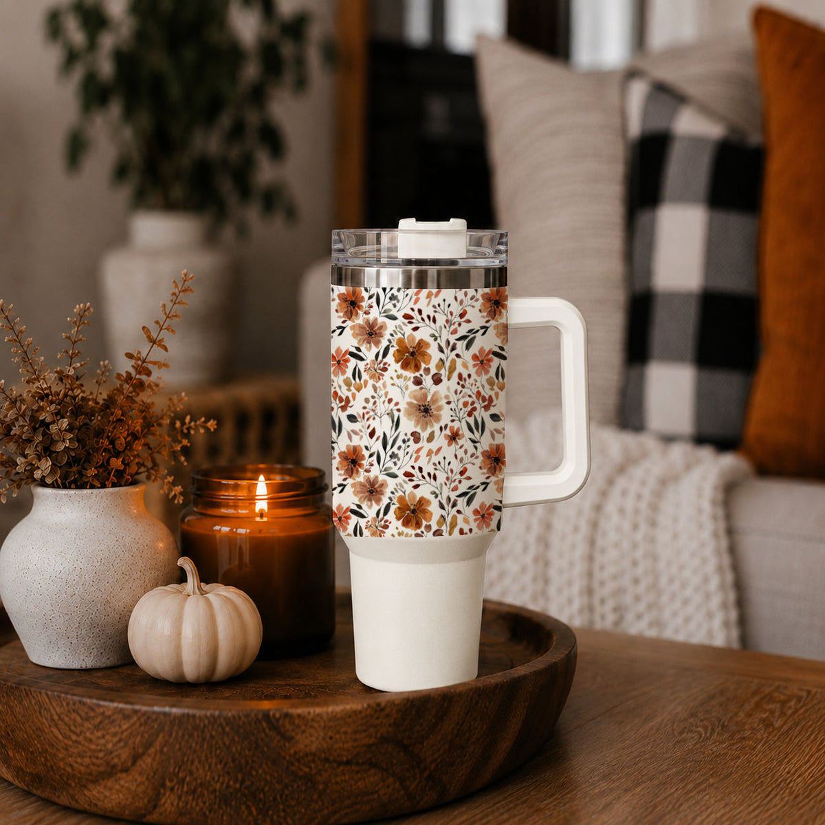 Floral travel tumbler with clear lid and straw, standing on a wooden tray