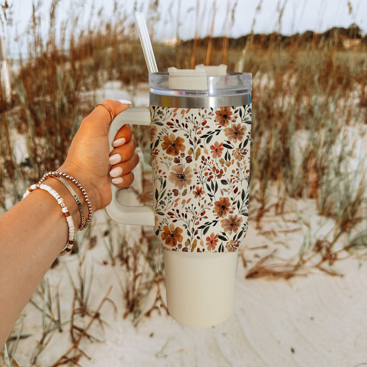 Floral 40oz tumbler held in hand, floral print with clear lid and straw, white body