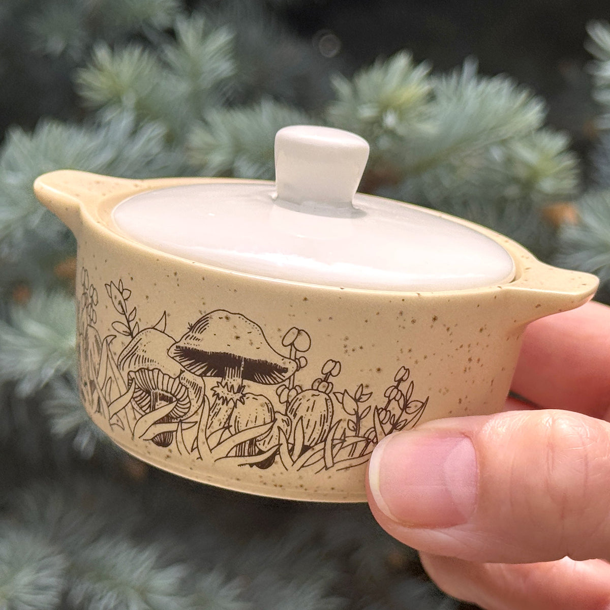 Beige ceramic trinket box with white lid; forest animal engraving along side