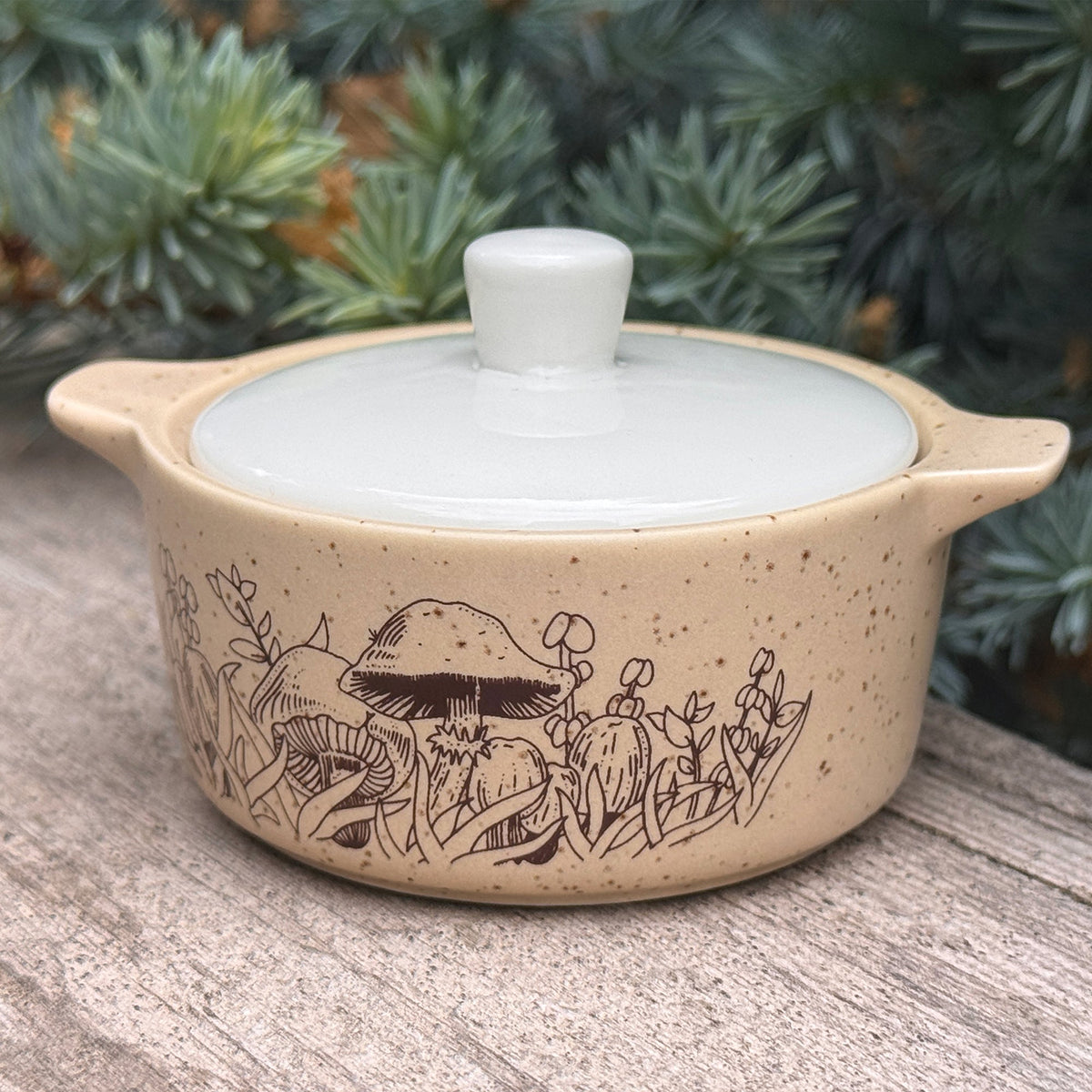 Beige ceramic trinket box with white lid and forest scene engraving on front
