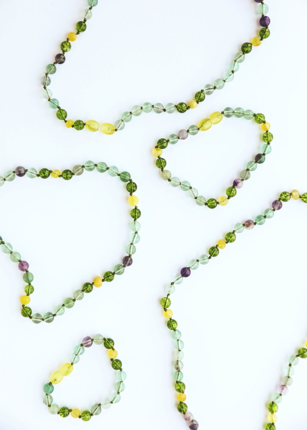 Gemstone bead necklace strand with green, yellow, and purple faceted stones