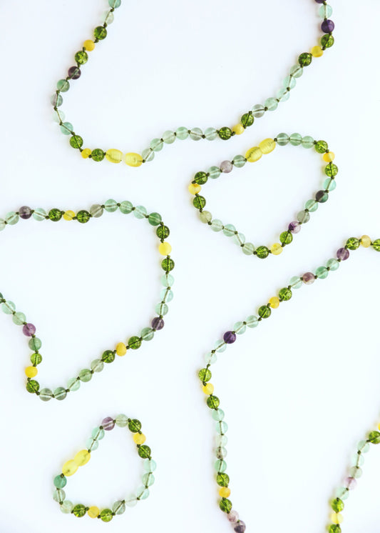 Gemstone bead necklace strand with green, yellow, and purple faceted stones