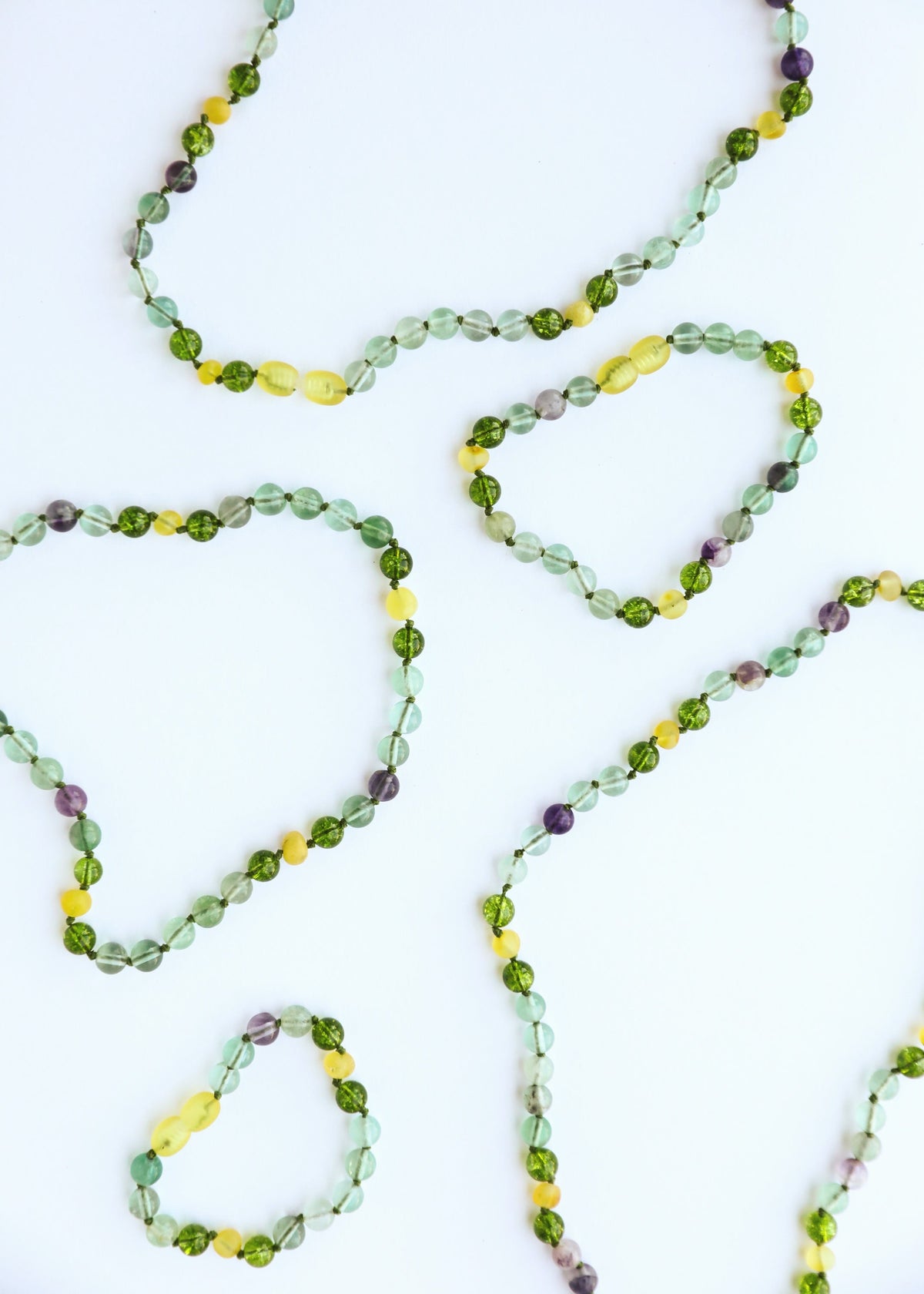 Multiple gemstone beaded bracelets and anklets with green, yellow, purple round beads