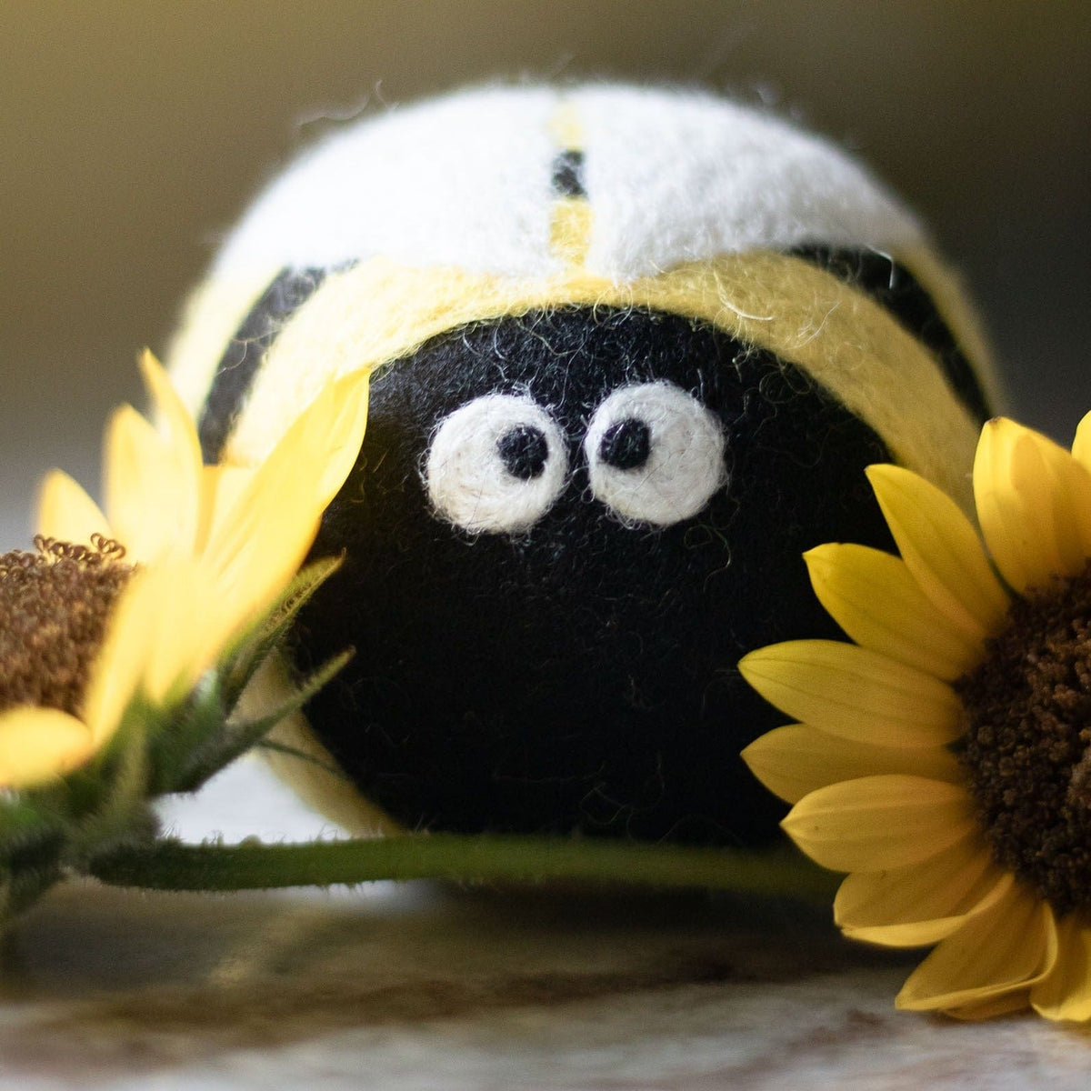 Close-up of plush bee dryer ball, yellow-and-black striped with white cartoon eyes